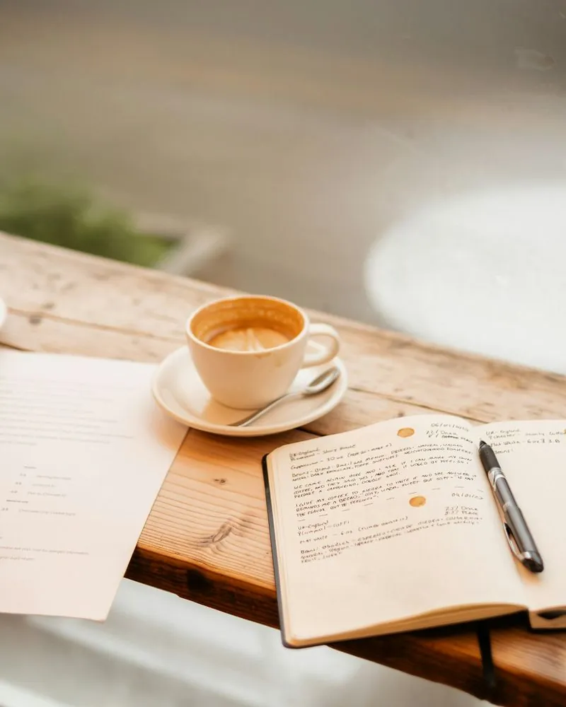 Notebook and a cup of coffee on a wooden window ledge in natural light